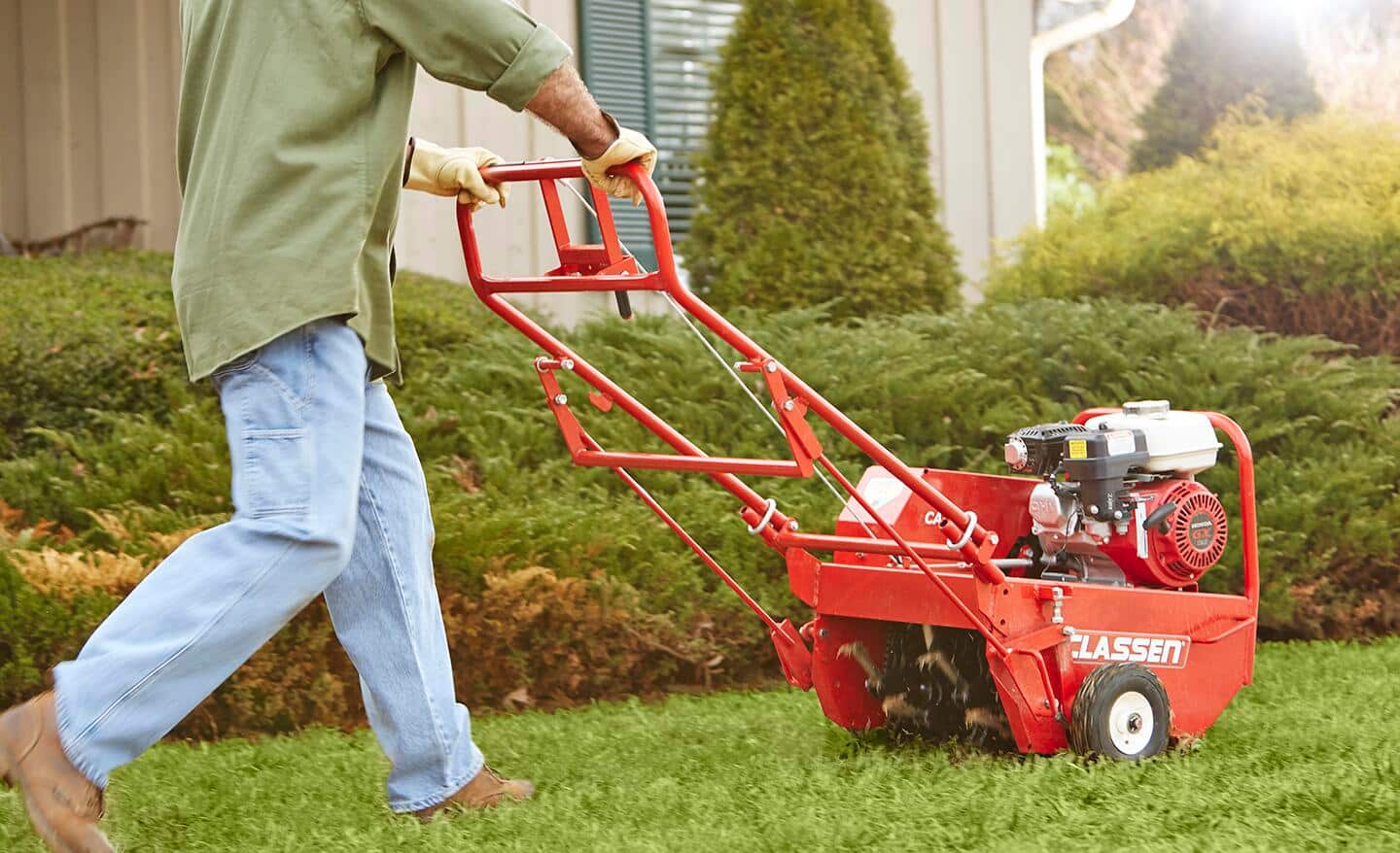 A person operating an aerator on a lawn. A person operating an aerator on a lawn.