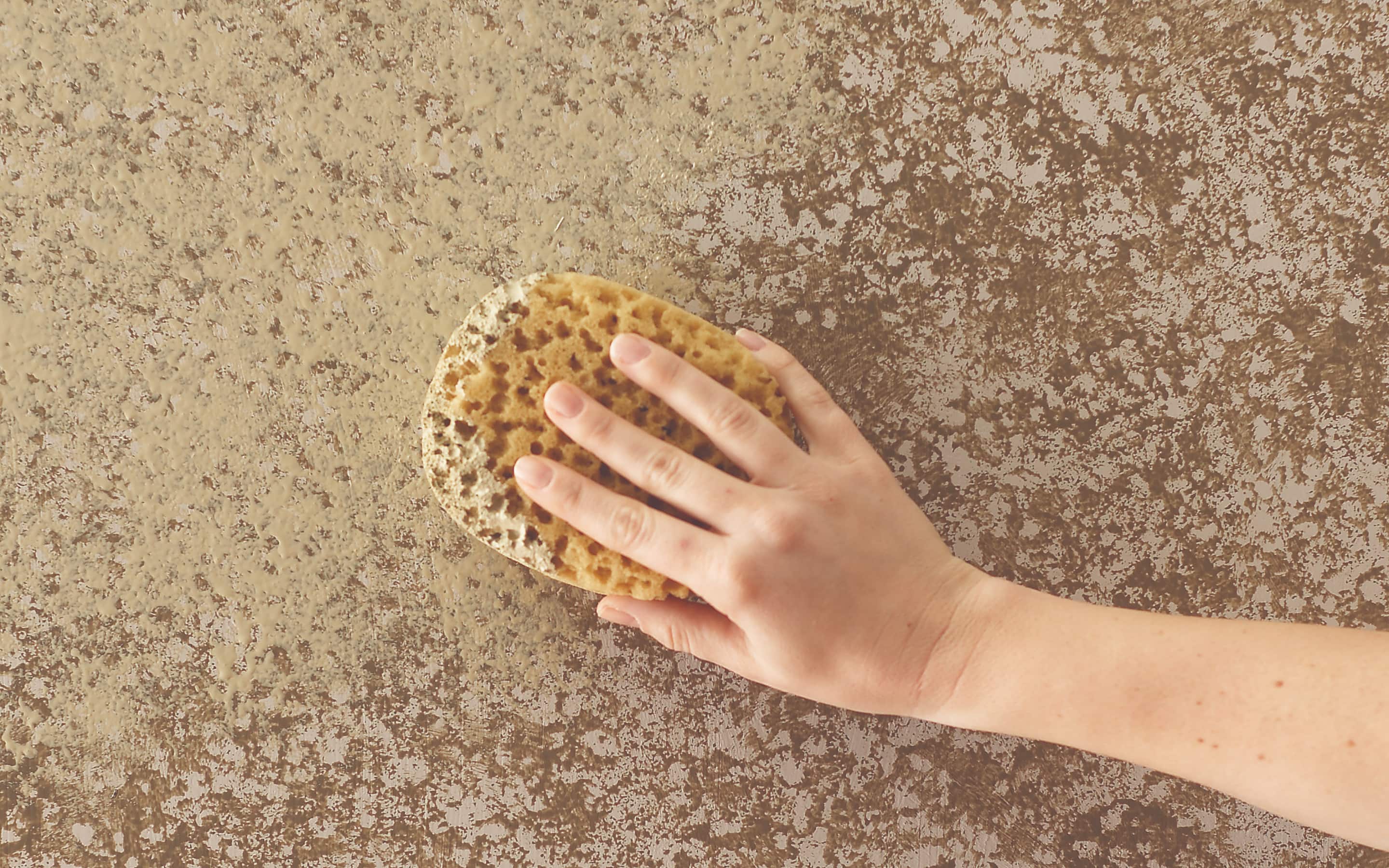 A person sponging paint onto a wall. A person sponging paint onto a wall.