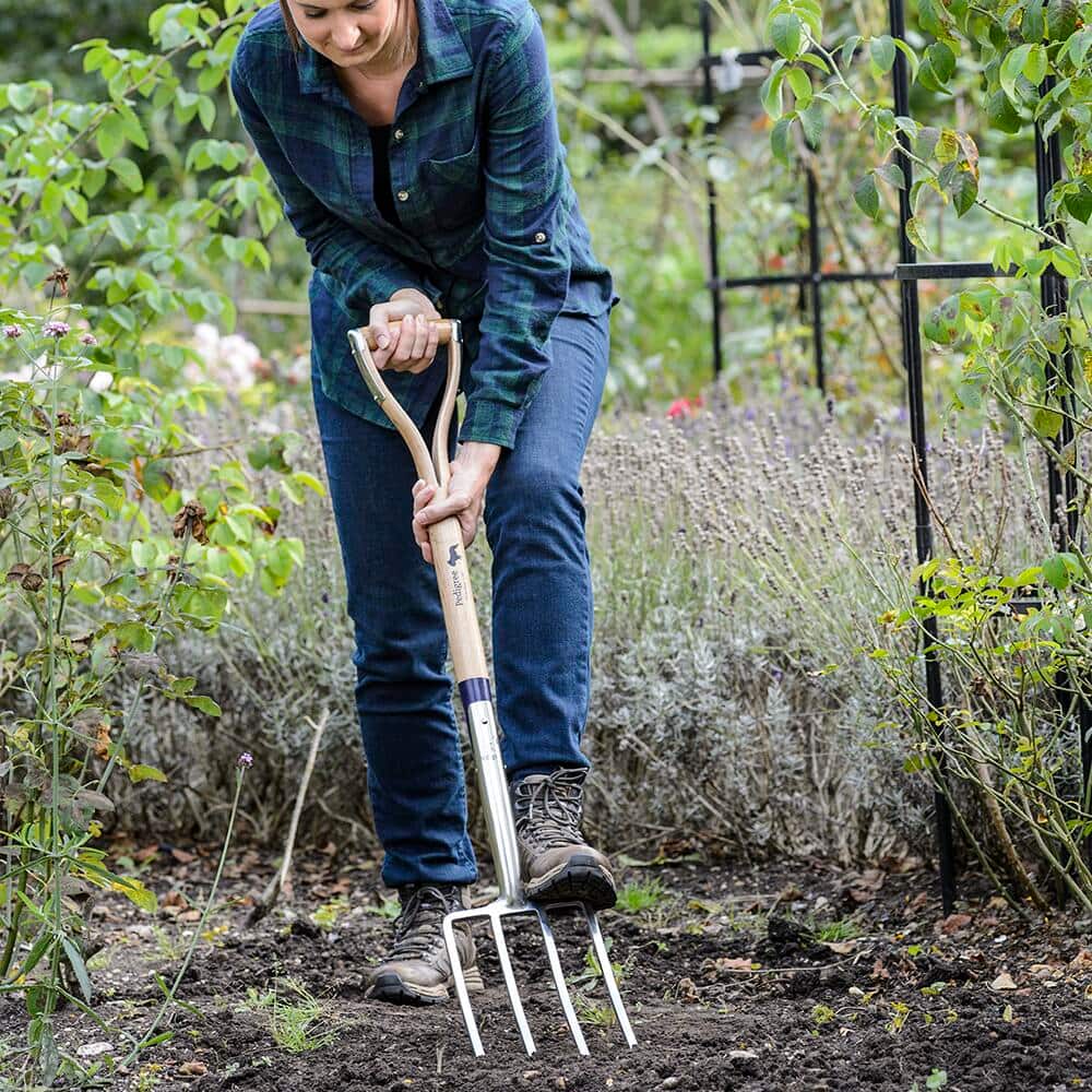 Gardener using a garden fork to refresh soil 
