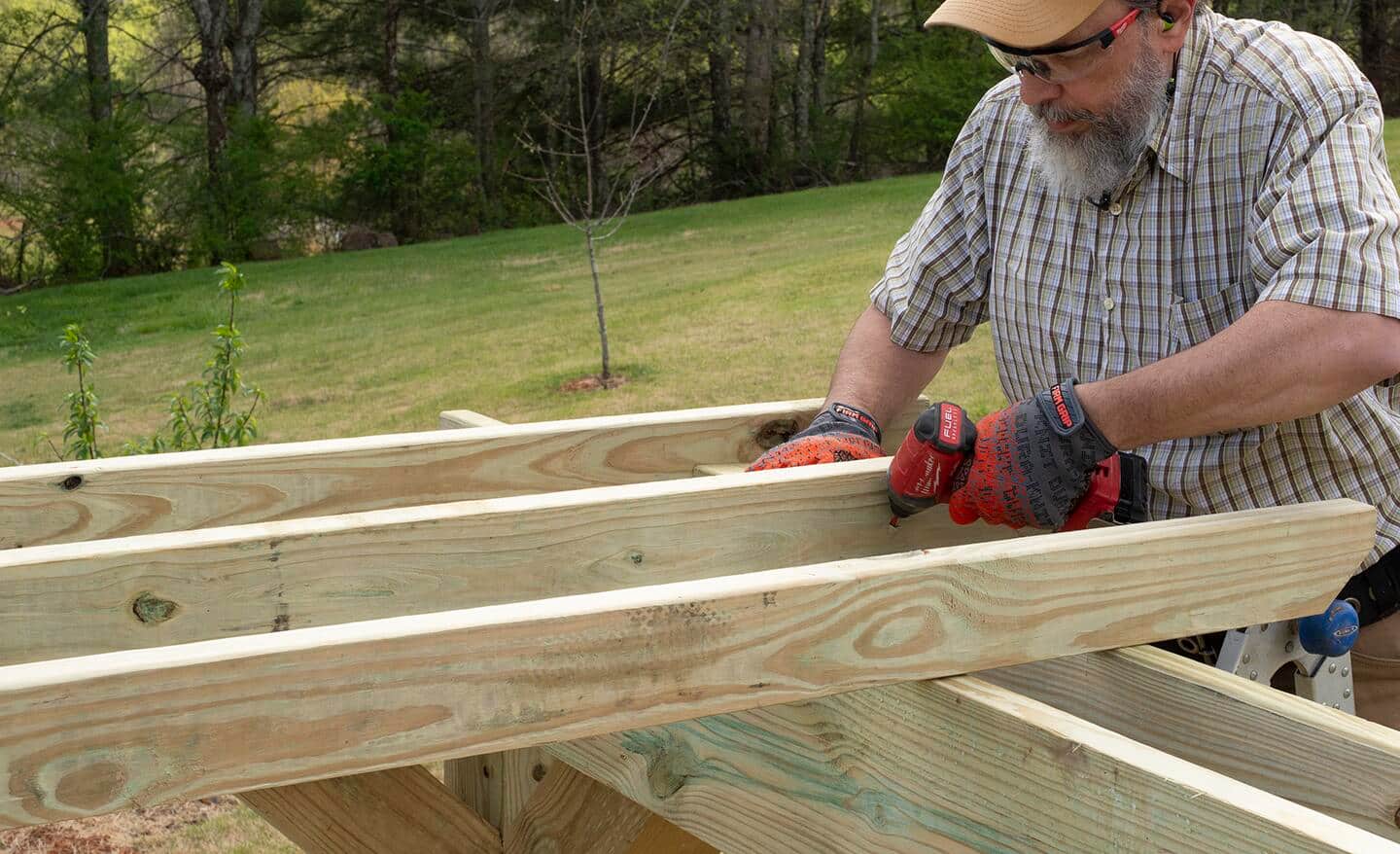 Slats are fastened to the top of a pergola by thumbnailing screws.