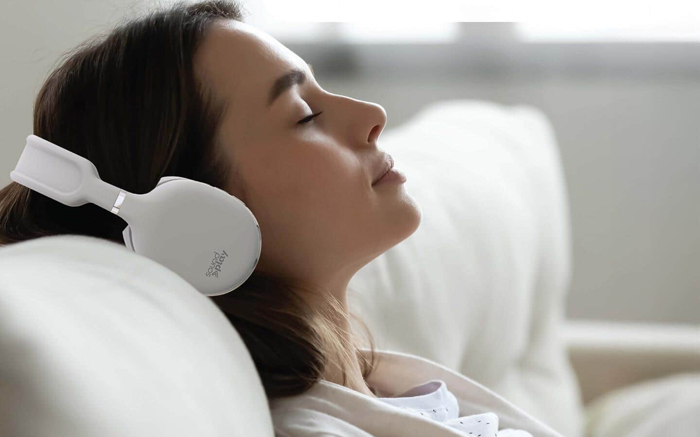 Someone reclining on a sofa wearing wireless smart headphones. Someone reclining on a sofa wearing wireless smart headphones.