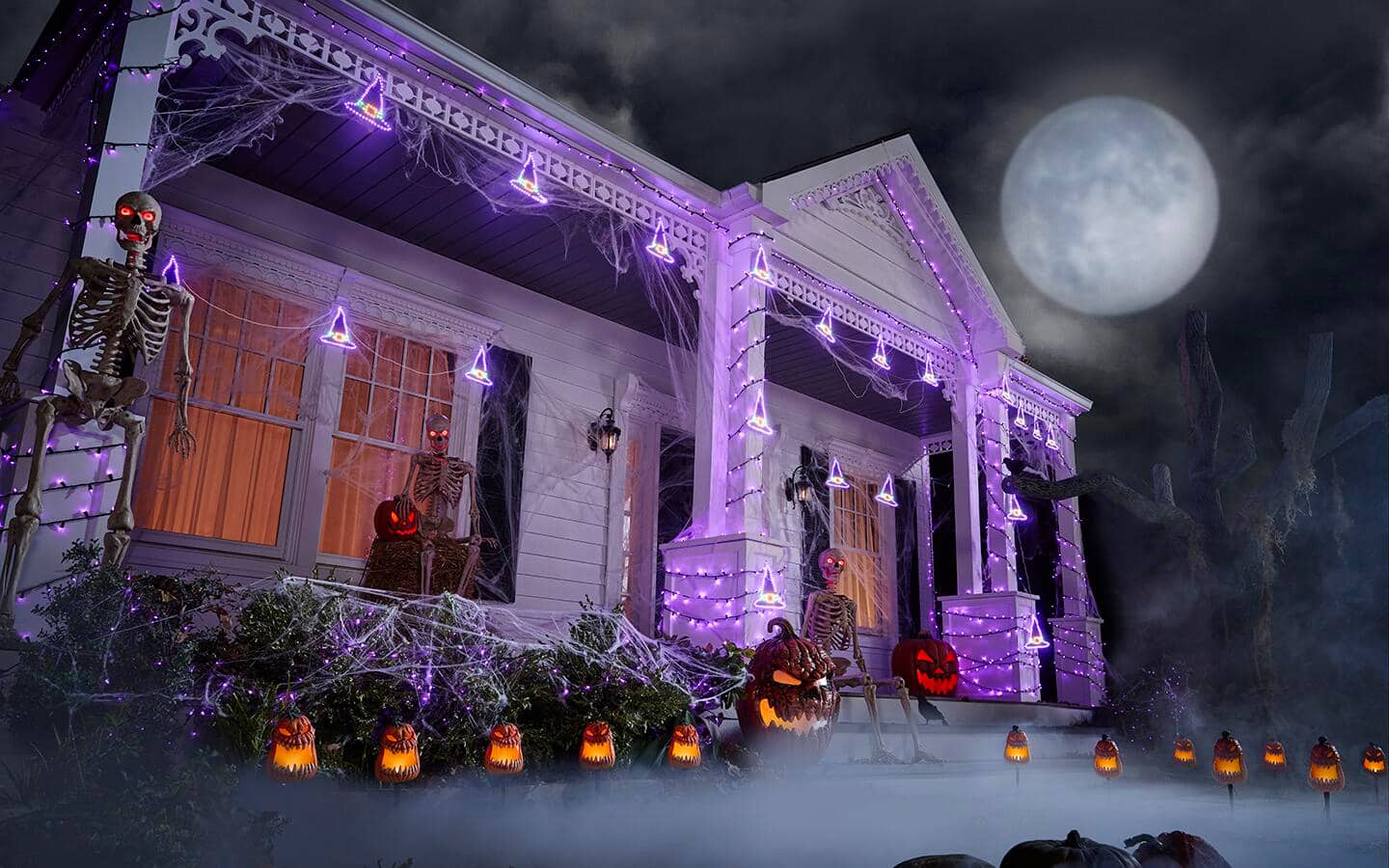 A front porch decorated with colorful light strands and glowing Halloween decor.