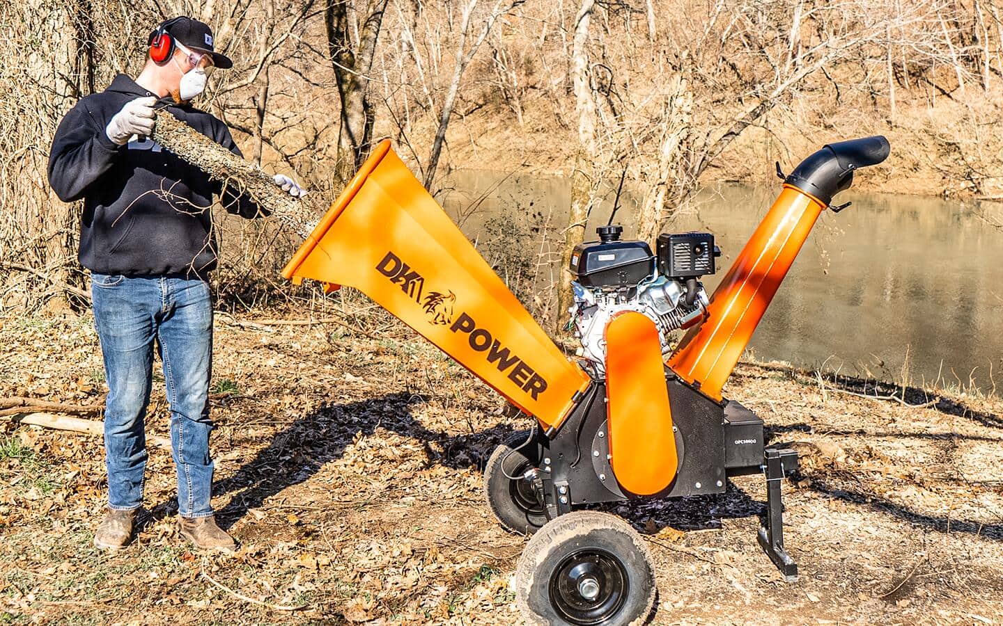 A person loads a piece of wood into a chipper shredder machine.