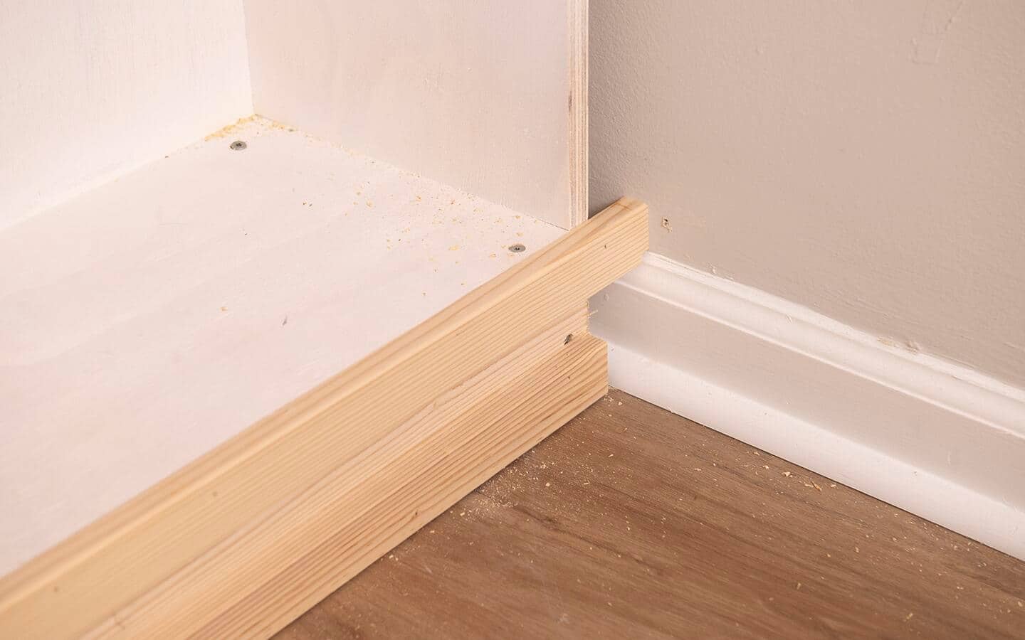 Piece of the face frame of a built in shelving unit where they meet the previously installed baseboard and shoe molding.
