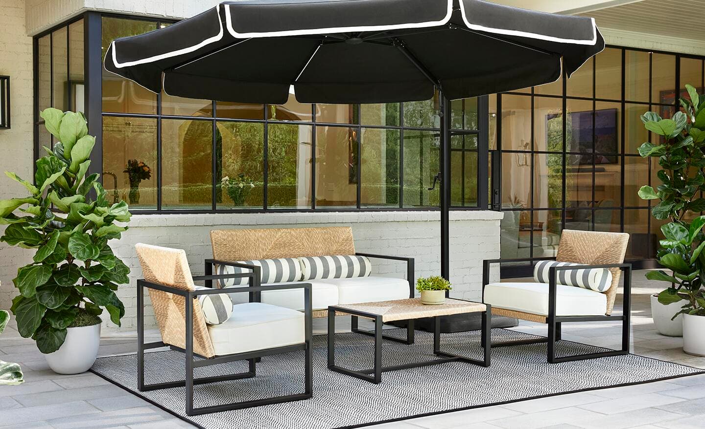 A reinforced aluminum patio set with white cushion chairs and a rectangular wicker coffee table under a patio umbrella.