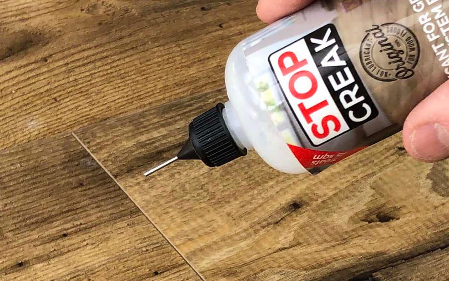 Lubricant being applied to squeaky hardwood floorboards.