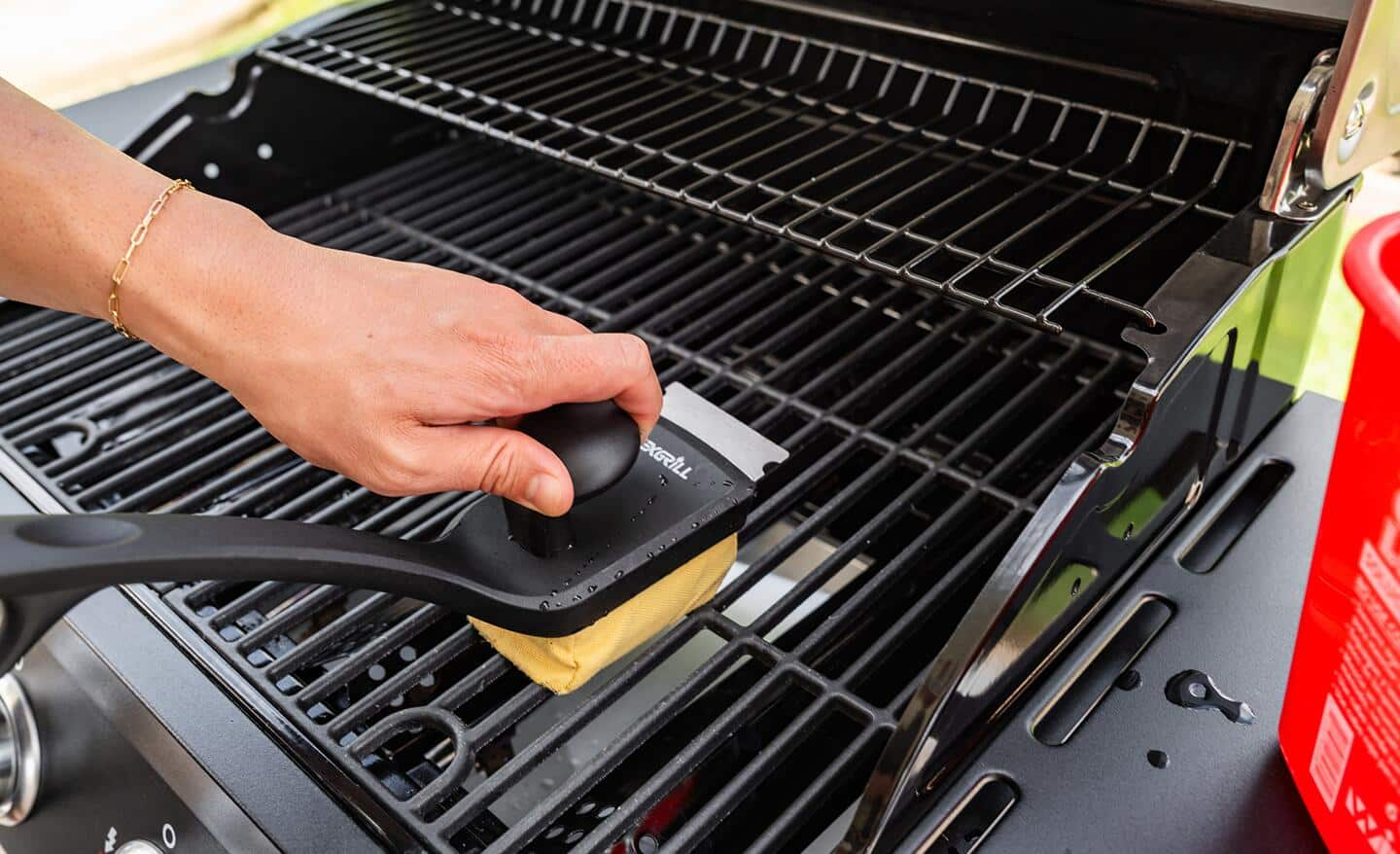 Someone cleaning a grill with a brush.