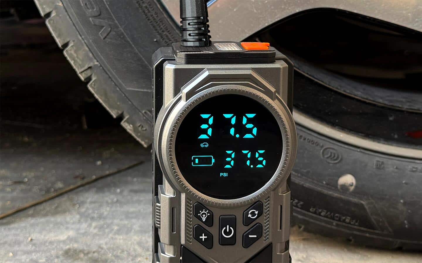 The digital display of a compact tire inflator reads 37.5 PSI. The digital display of a compact tire inflator reads 37.5 PSI.