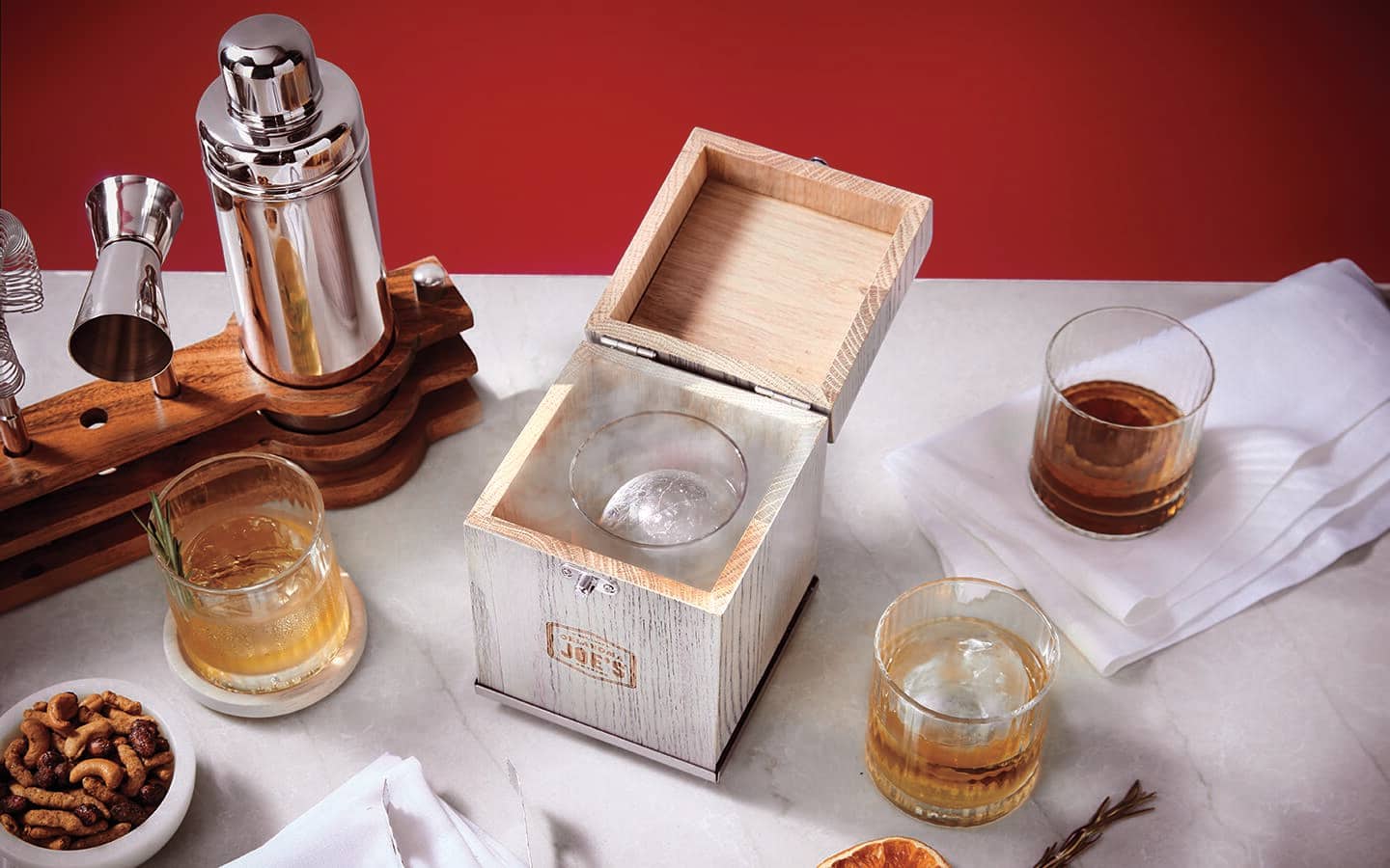 A silver bartender kit and highball glasses displayed with snacks. A silver bartender kit and highball glasses displayed with snacks.
