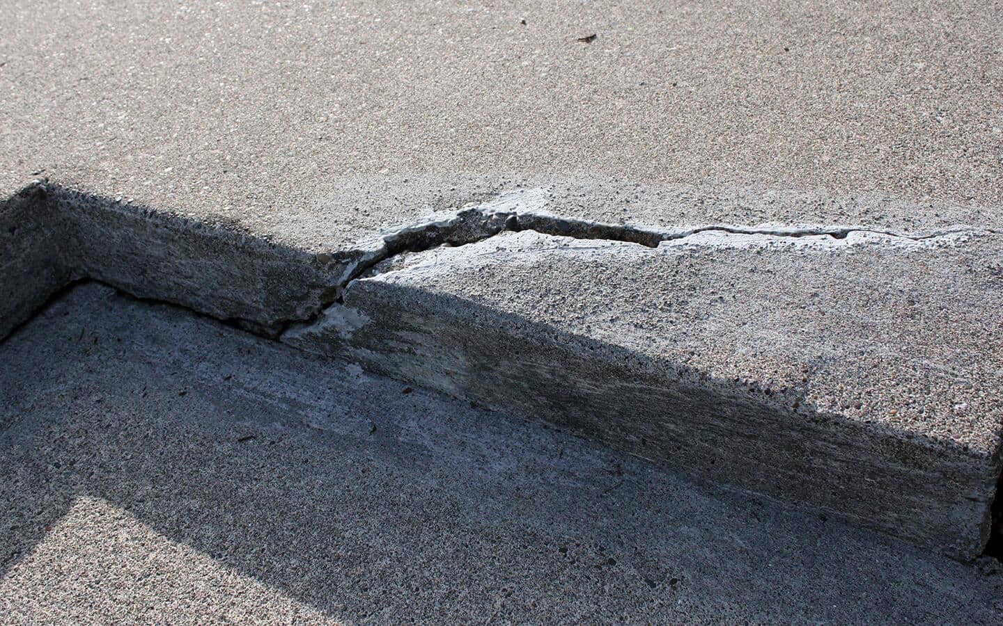 A deep crack runs through a concrete step. A deep crack runs through a concrete step.