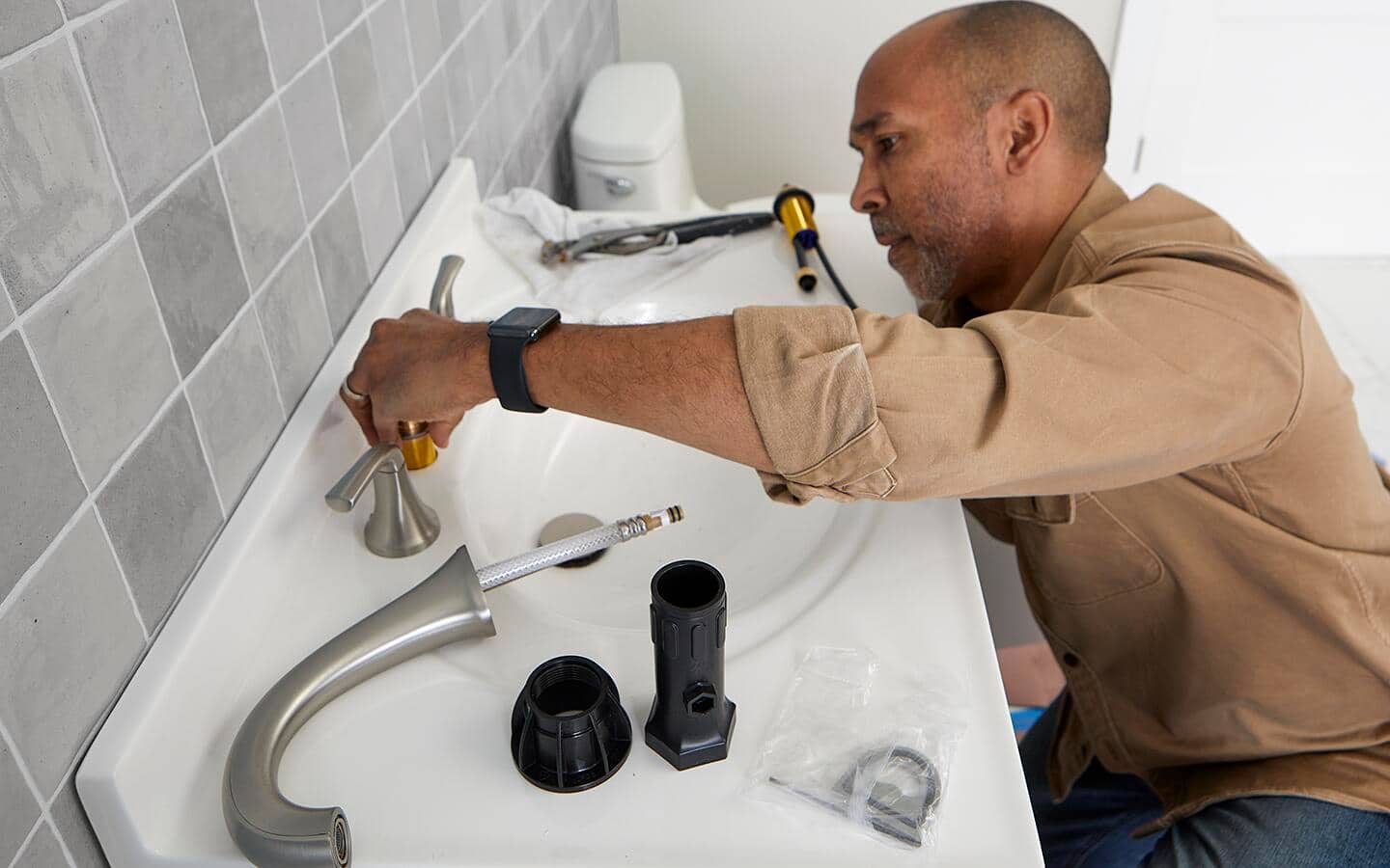 Person reassembling the faucet. Person reassembling the faucet.