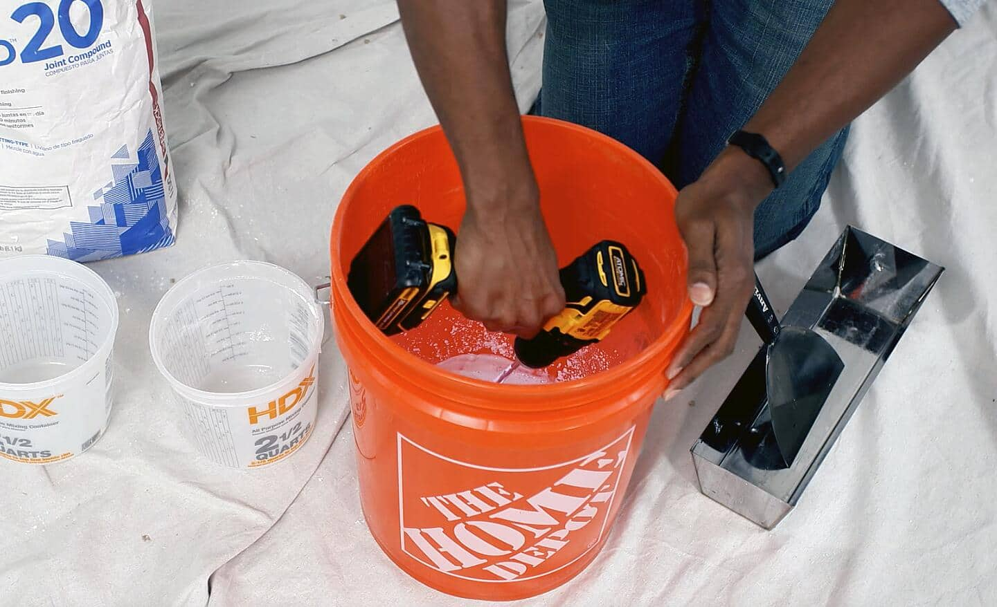 Someone mixing drywall mud in a bucket.