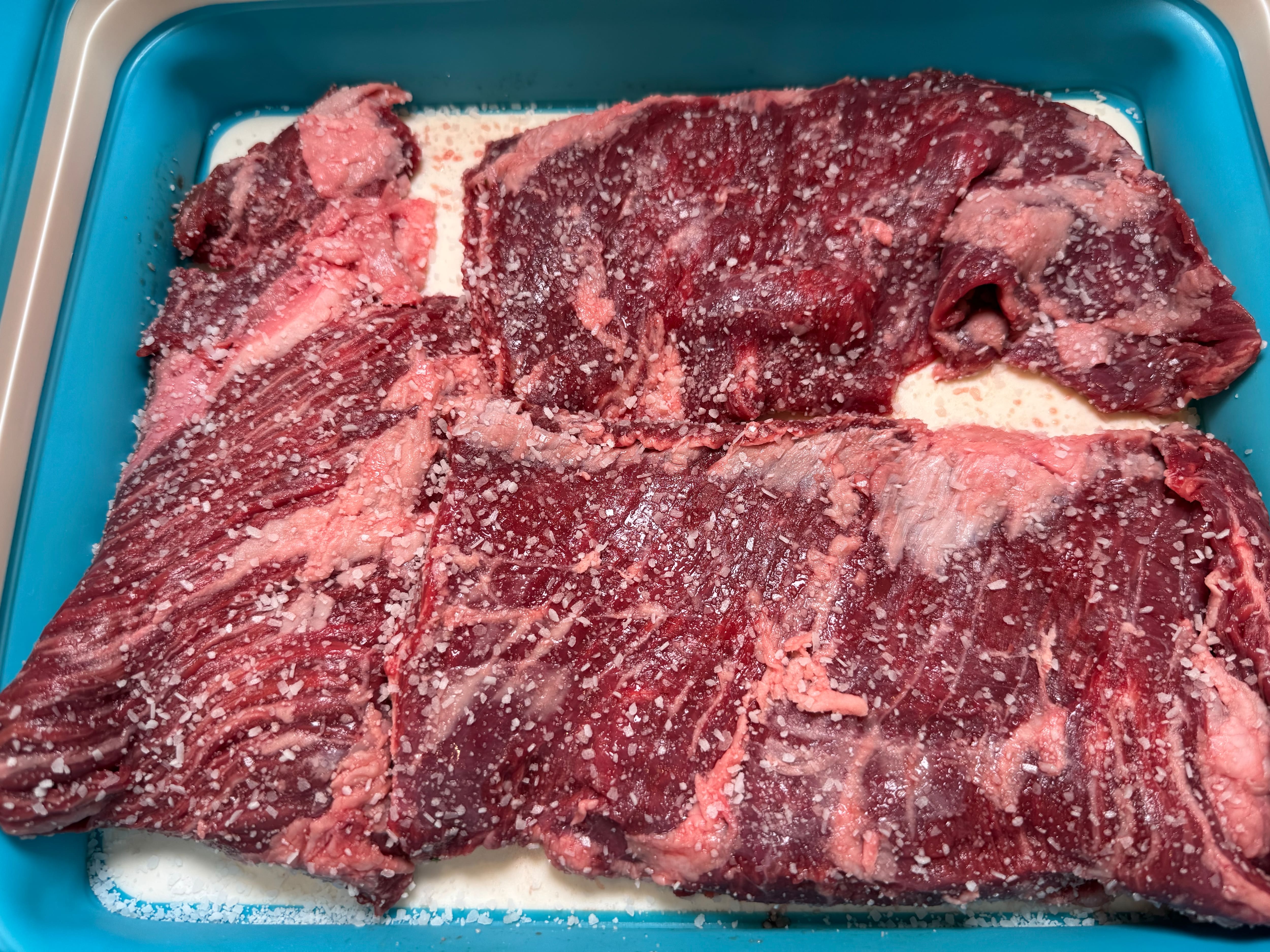 Raw steak sitting over a bed of salt and coated with kosher salt. Raw steak sitting over a bed of salt and coated with kosher salt.