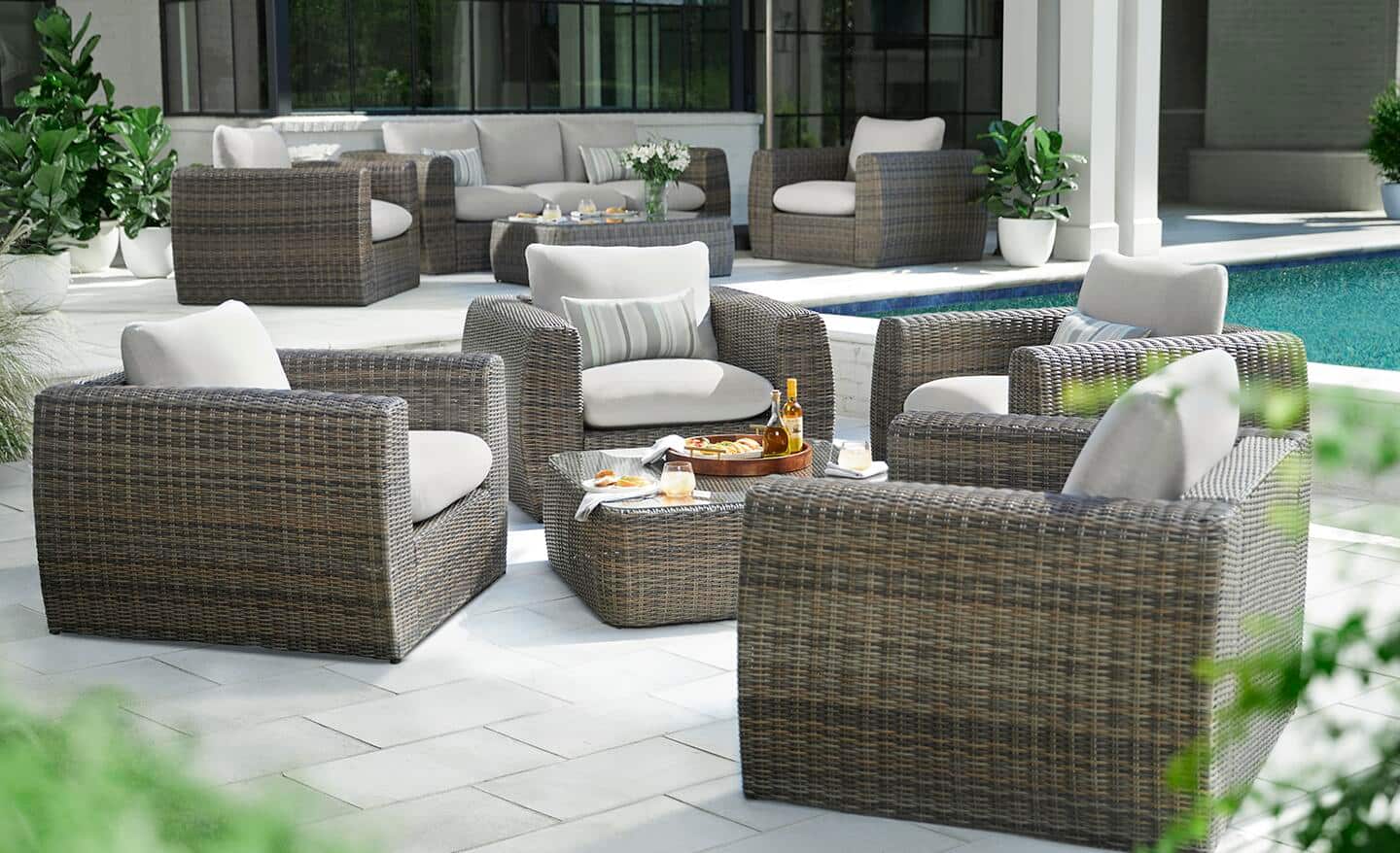 Four outdoor lounge chairs surround a matching gray coffee table on a deck near a pool.