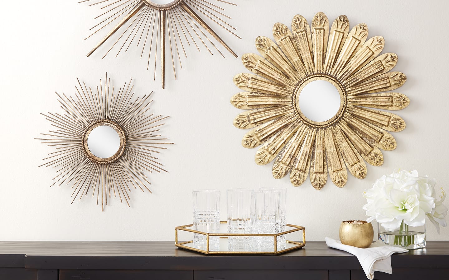 Gold mirrors hung over a black dresser