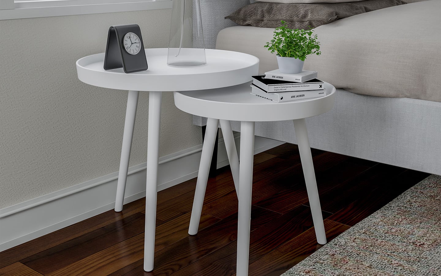 Two white nesting tables beside a bed