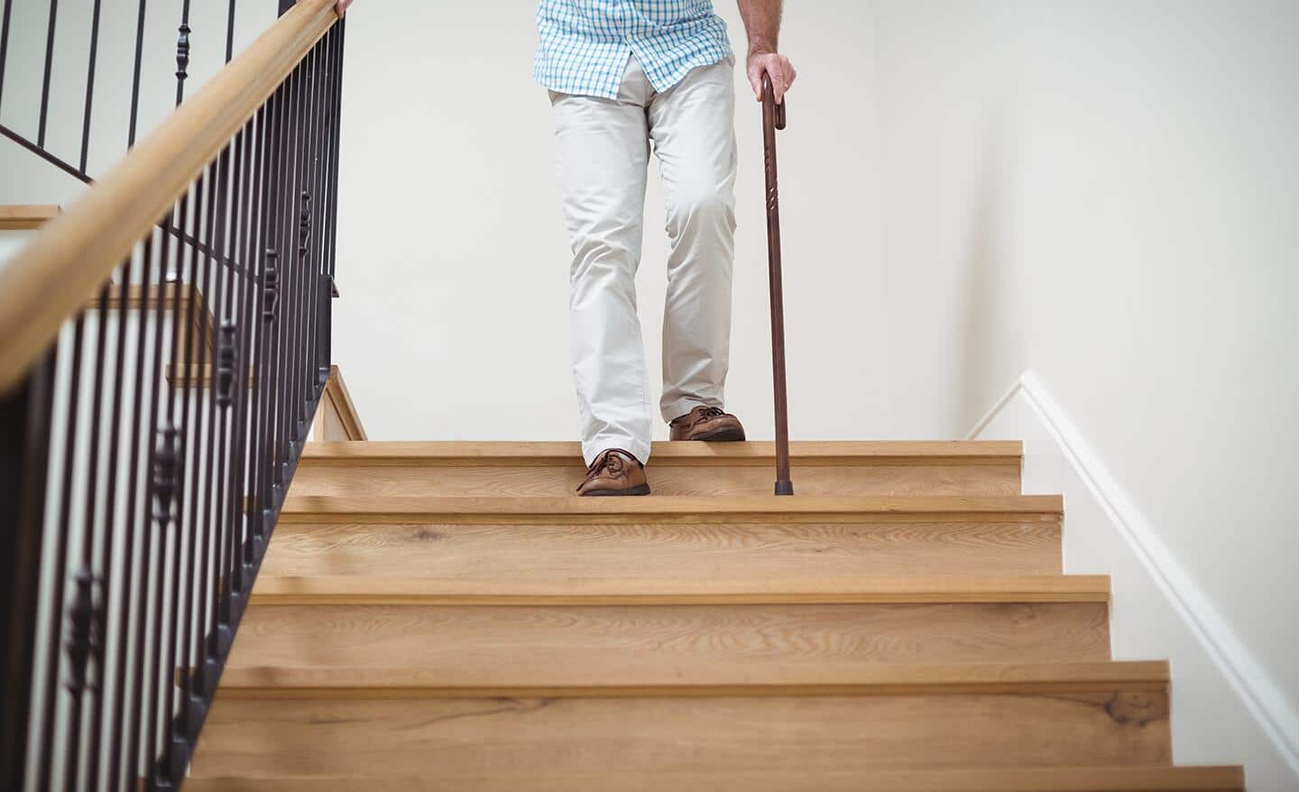 A man, using a walking cane, descends a stairway.