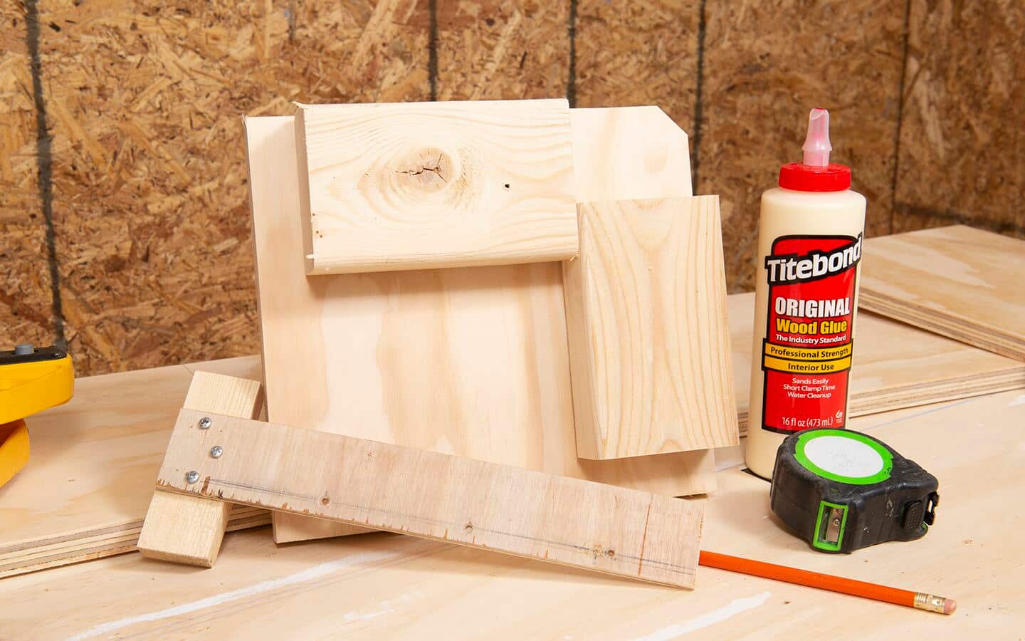 Two woodworking jigs, a tape measure, pencil and bottle of wood glue.