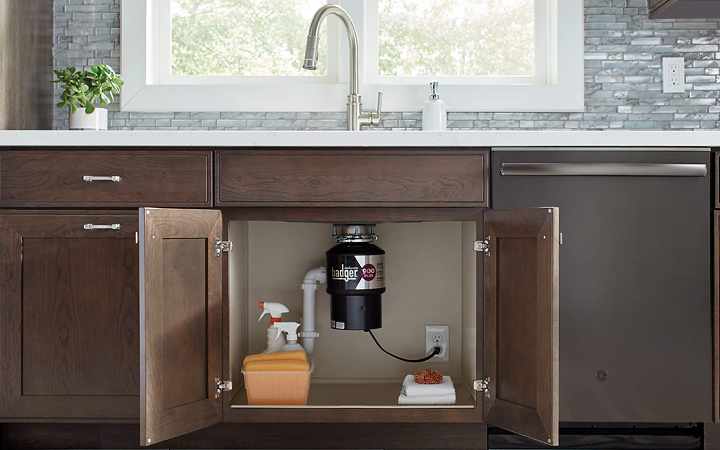 A garbage disposal under a kitchen sink, visible through two open doors of a kitchen cabinet.