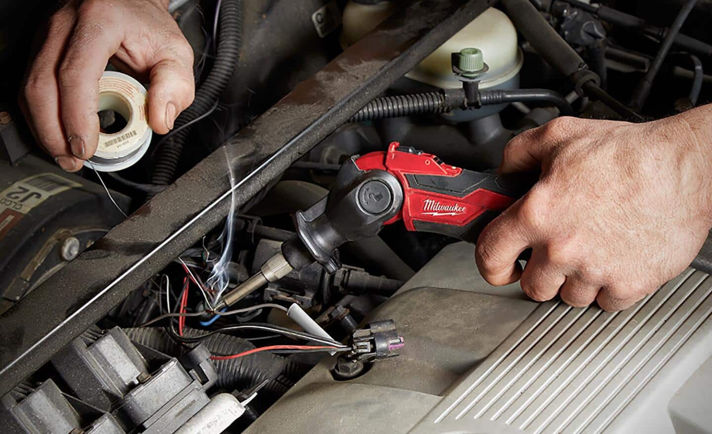 A battery powered soldering iron being used to make electrical connections in a vehicle.