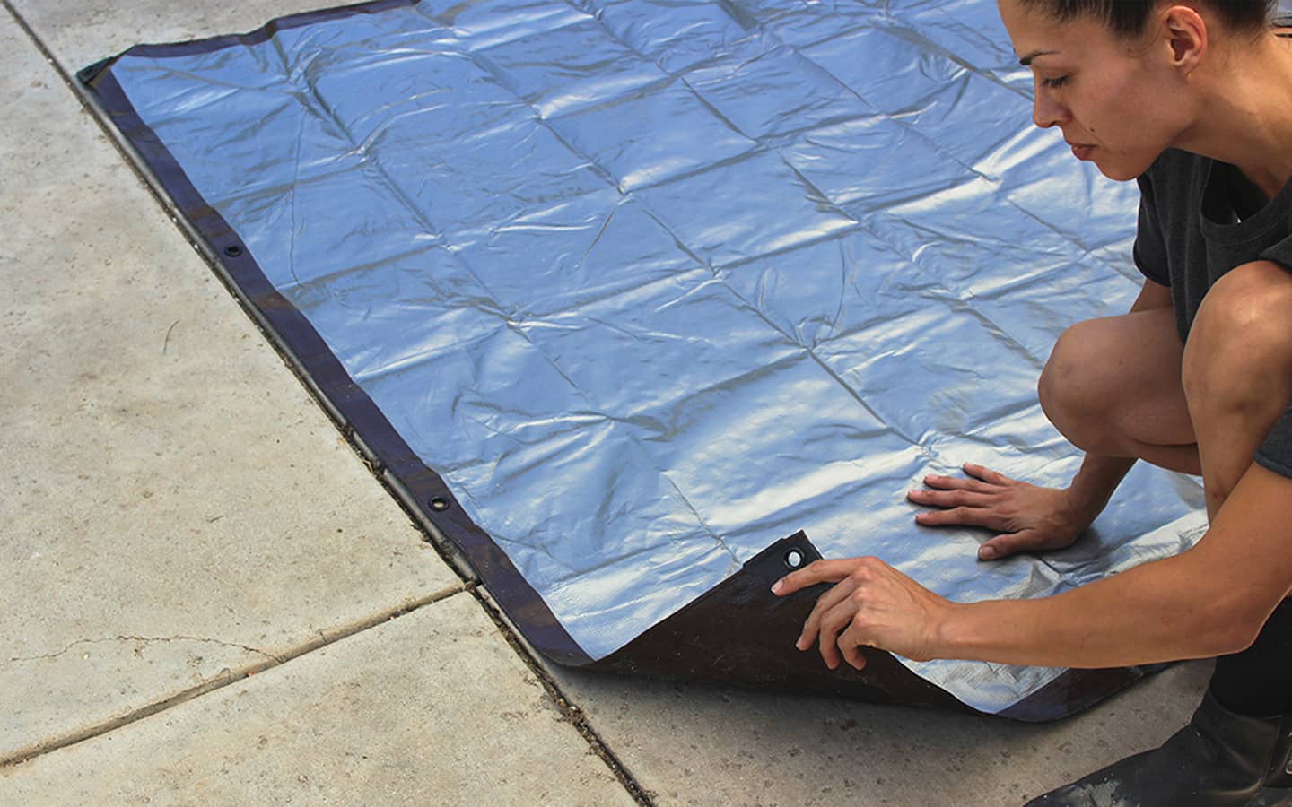 The tarp is unfolded and placed on the ground.