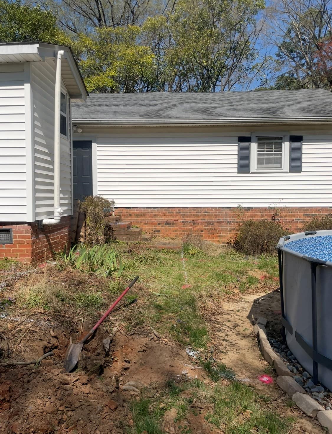 Barren backyard with untamed landscaping and markings indicating electrical, water, and power lines.