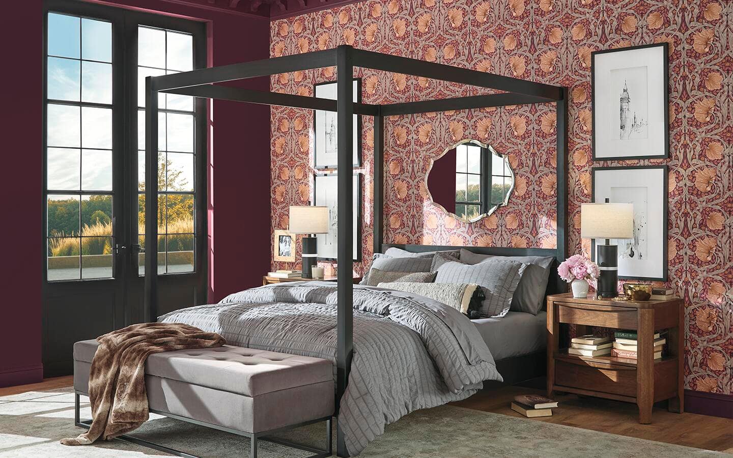 A poster bed in front of a bedroom wall covered in gold and red wallpaper.