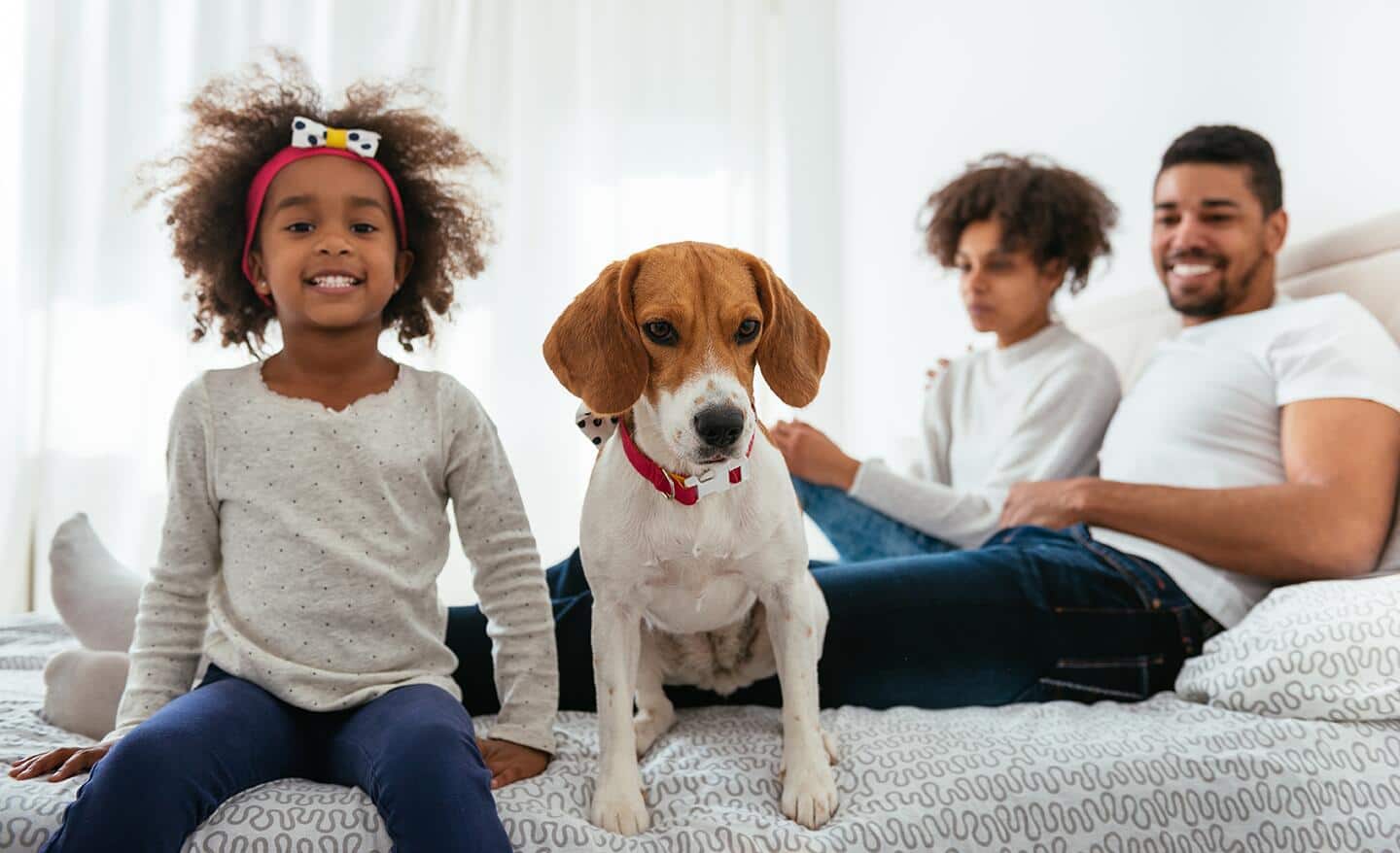 Parents relaxing in a California king size bed with their child and small dog. Parents relaxing in a California king size bed with their child and small dog.