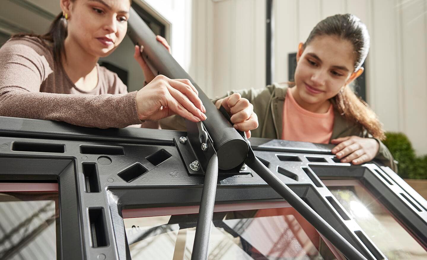 Mom and daughter securing basketball backboard to pole.