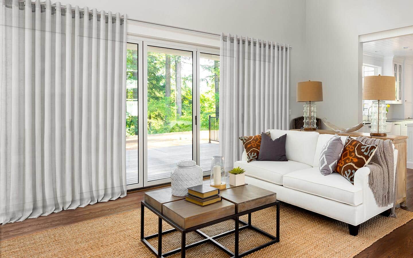 Long, sheer, white curtains covering glass doors in a living room. Long, sheer, white curtains covering glass doors in a living room.