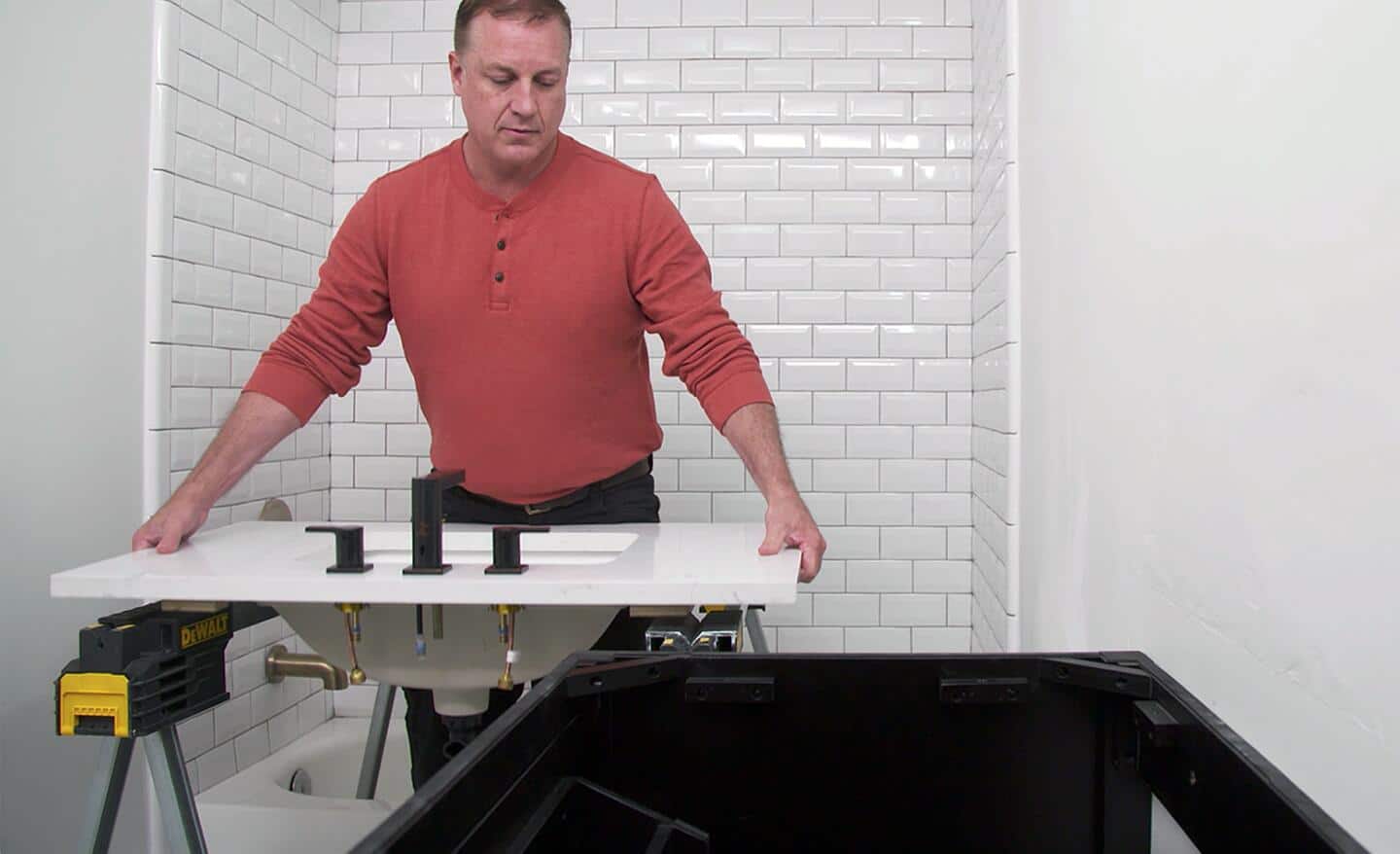 A man adding a sink to a vanity in a bathroom. 
