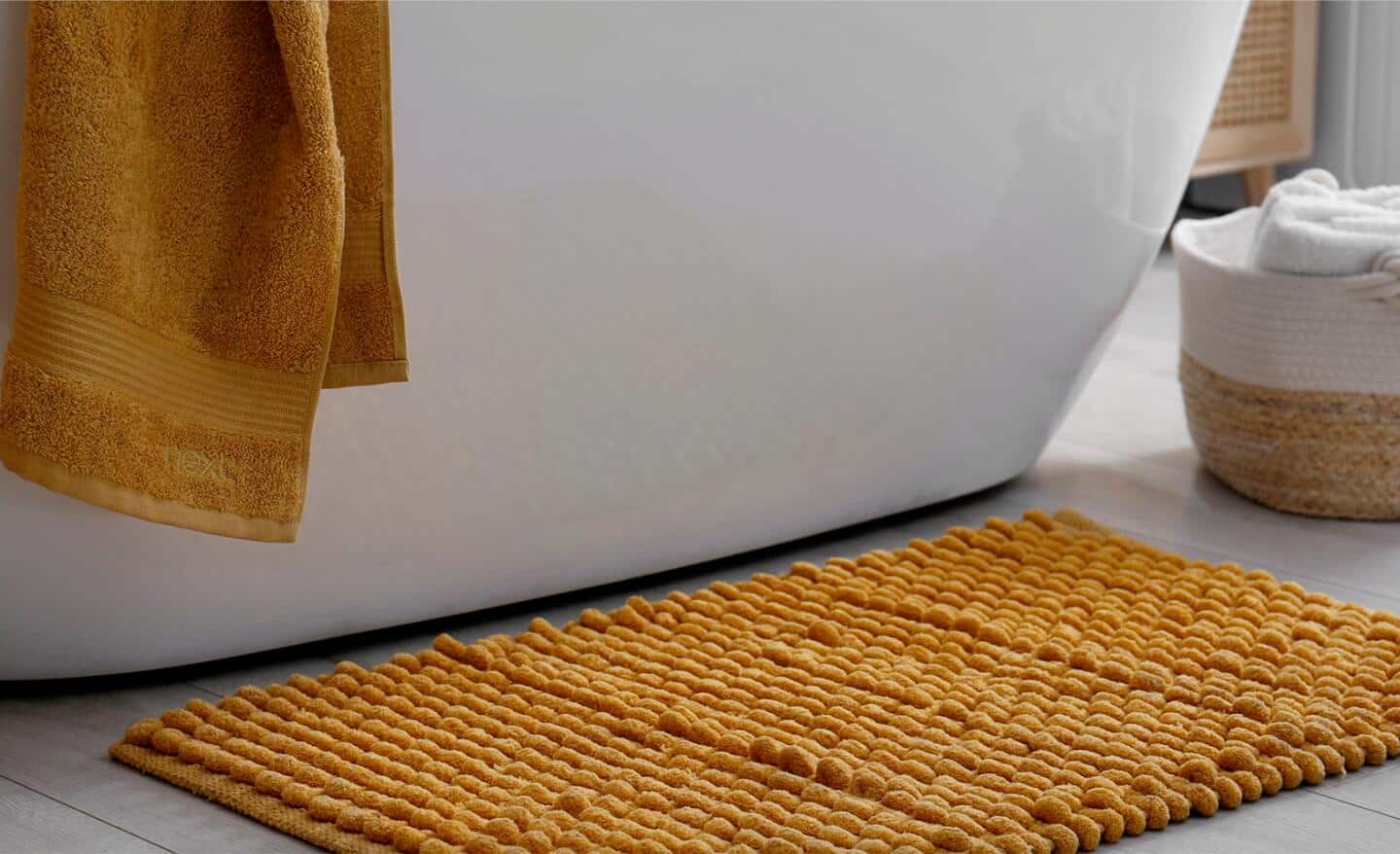A gold bath mat made out of chunky cotton yarn.