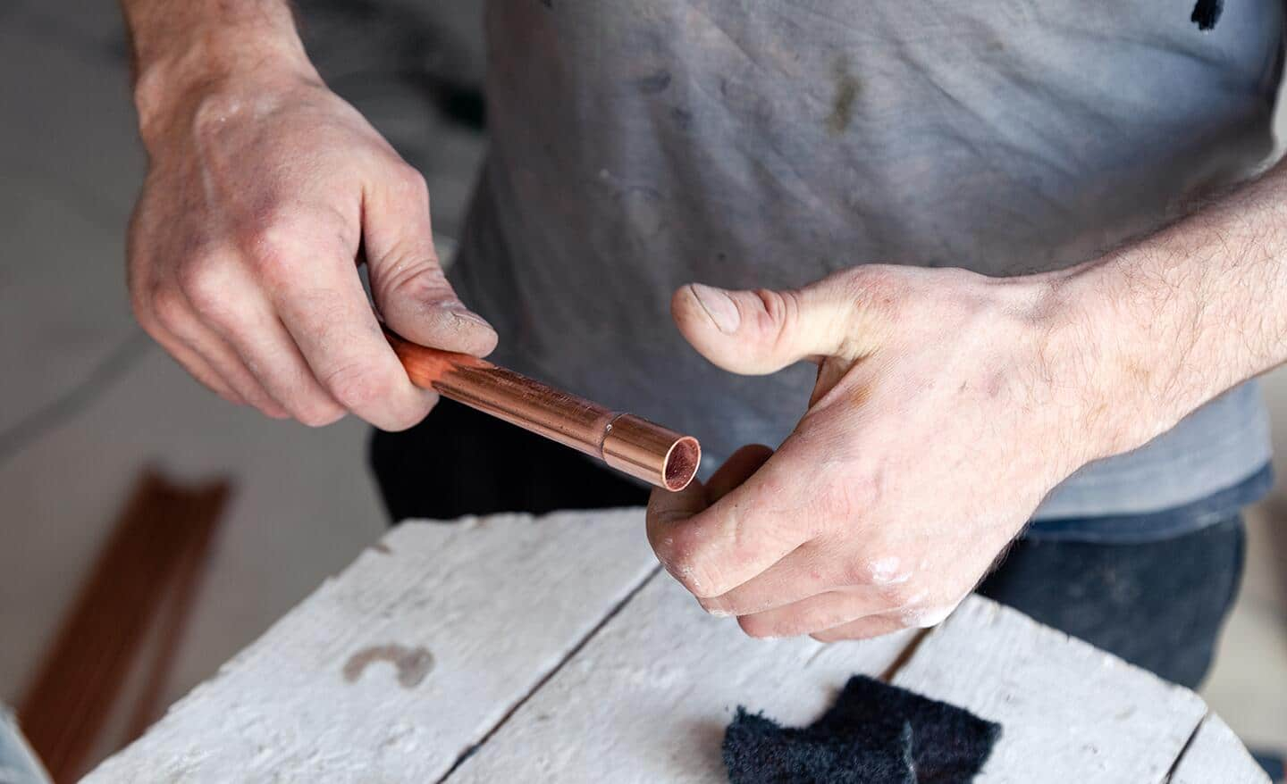 A man follows the first rule of soldering, all surfaces must be clean.