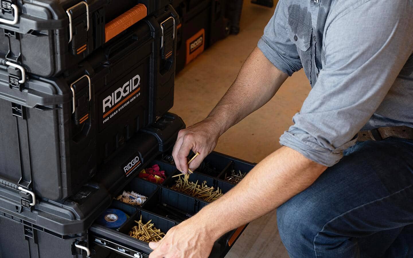 A man takes screws from a drawer in a modular tool storage system.
