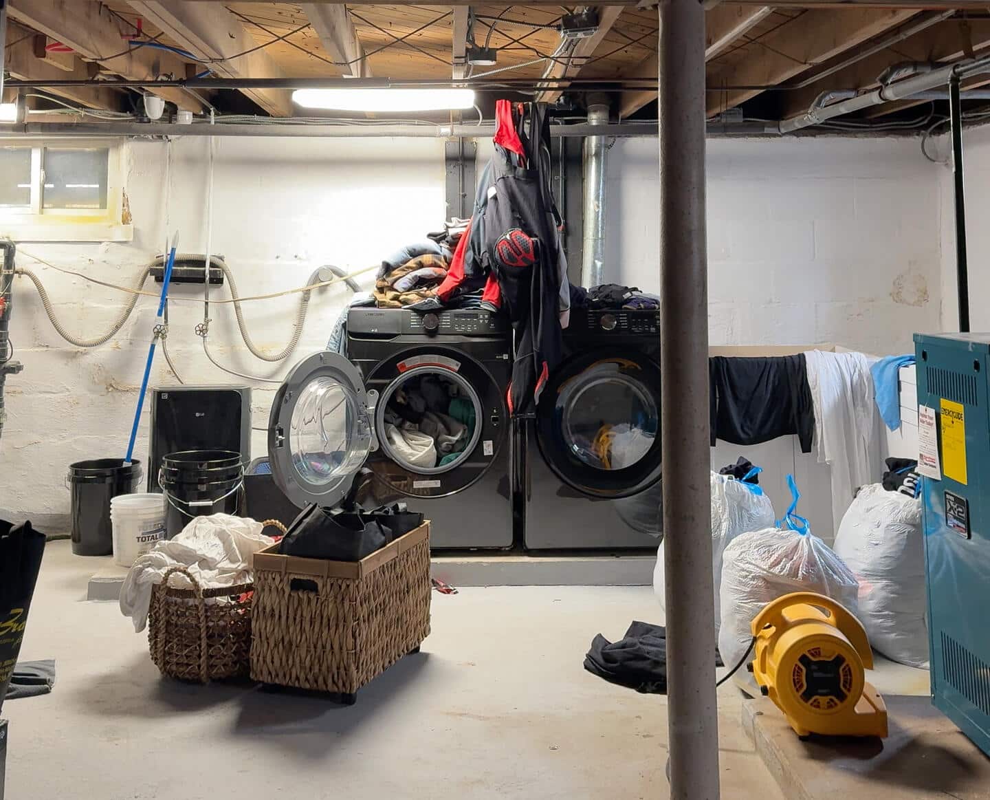 Before image of messy basement with full washer and dryer. 
