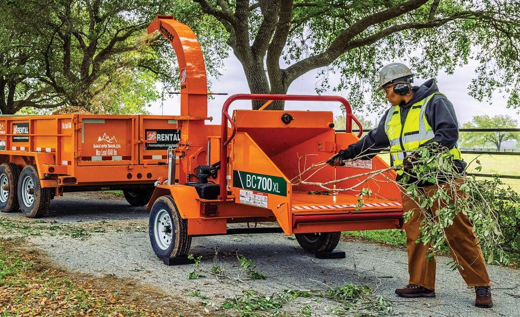 A Pro feeds a branch into a chipper. A Pro feeds a branch into a chipper.