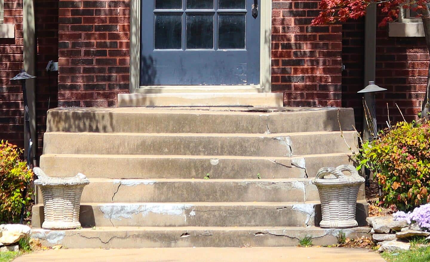 Cracked concrete steps leading up to a door.