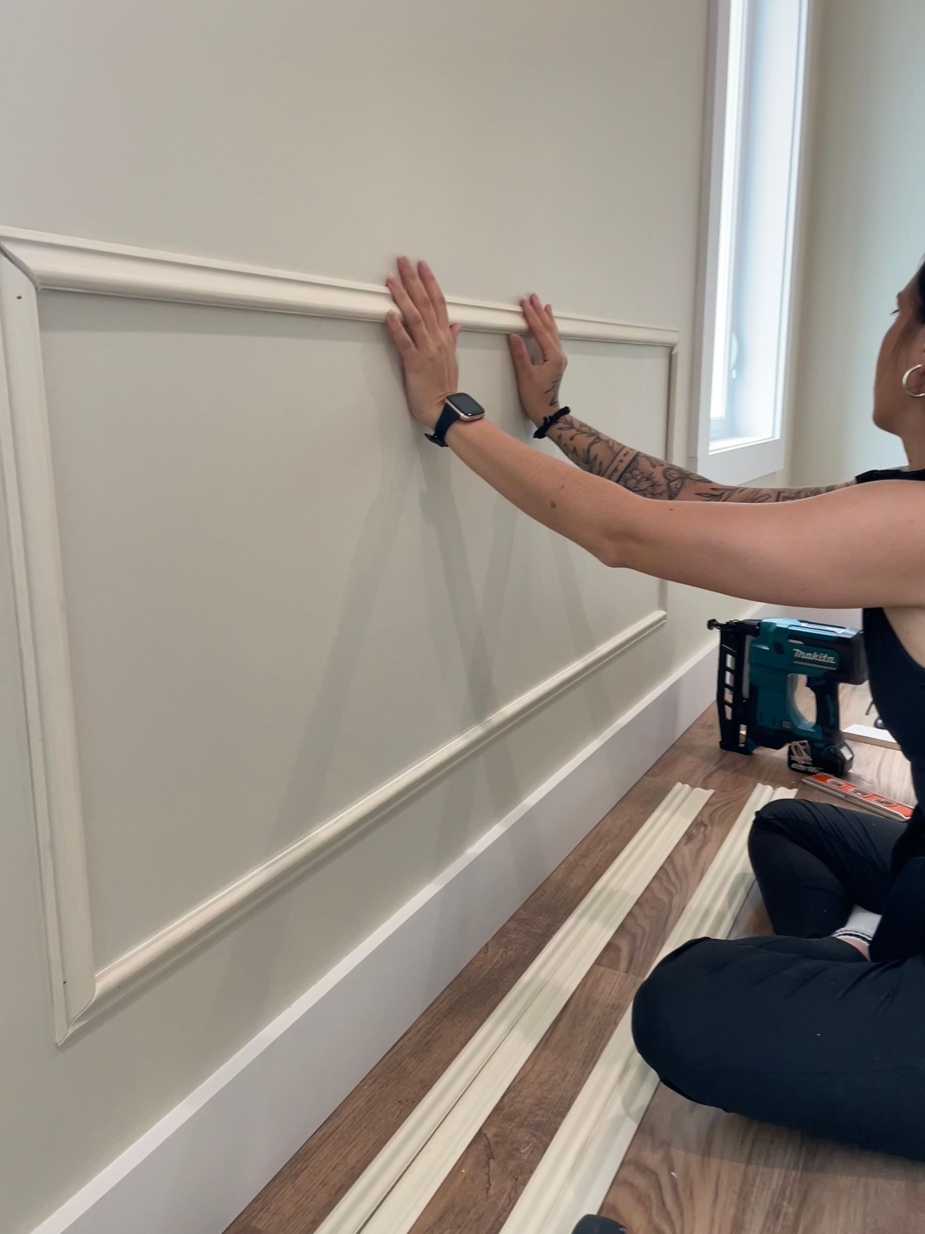 A person putting up trim on the wall