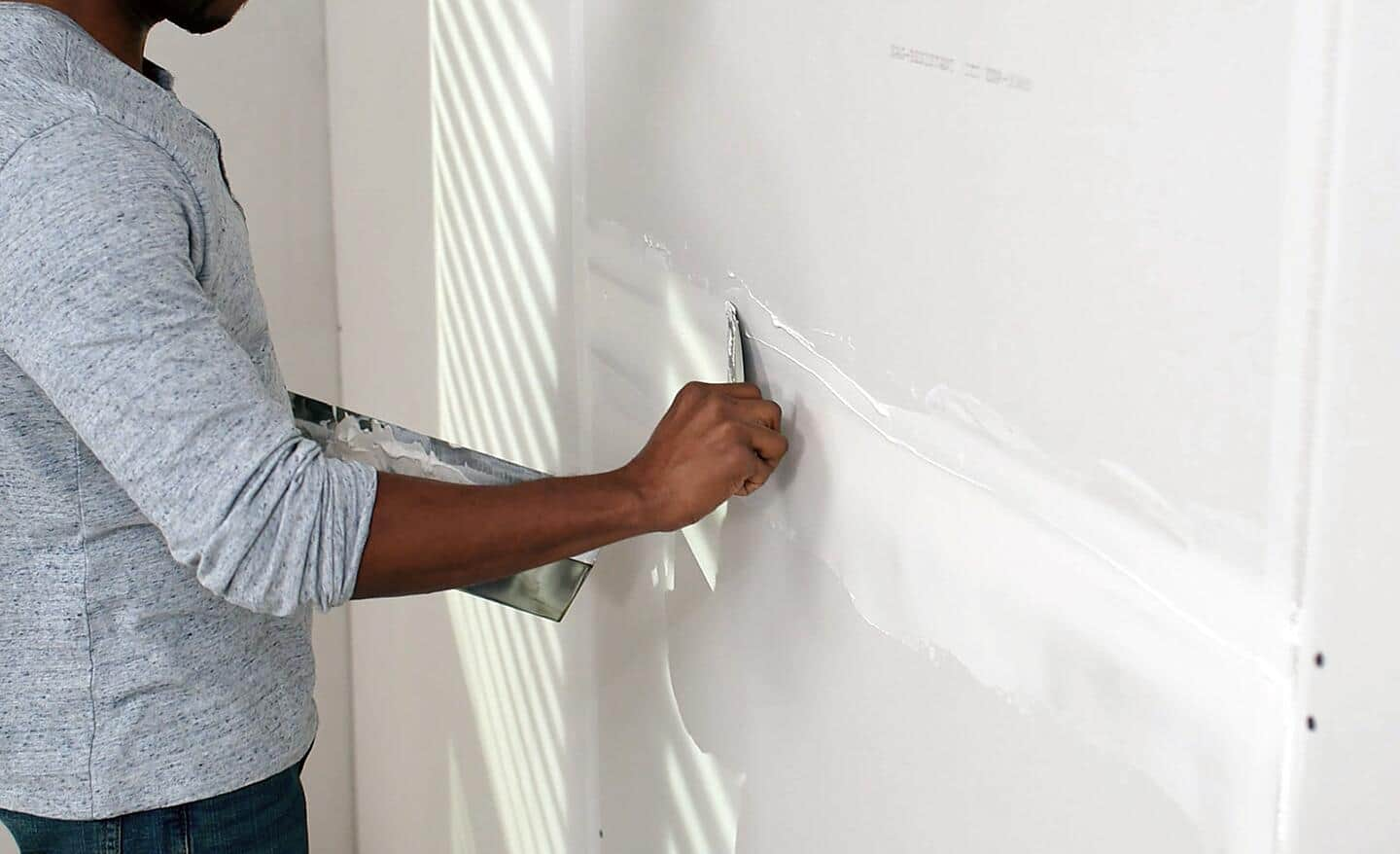 A worker covers a joint with drywall mud.