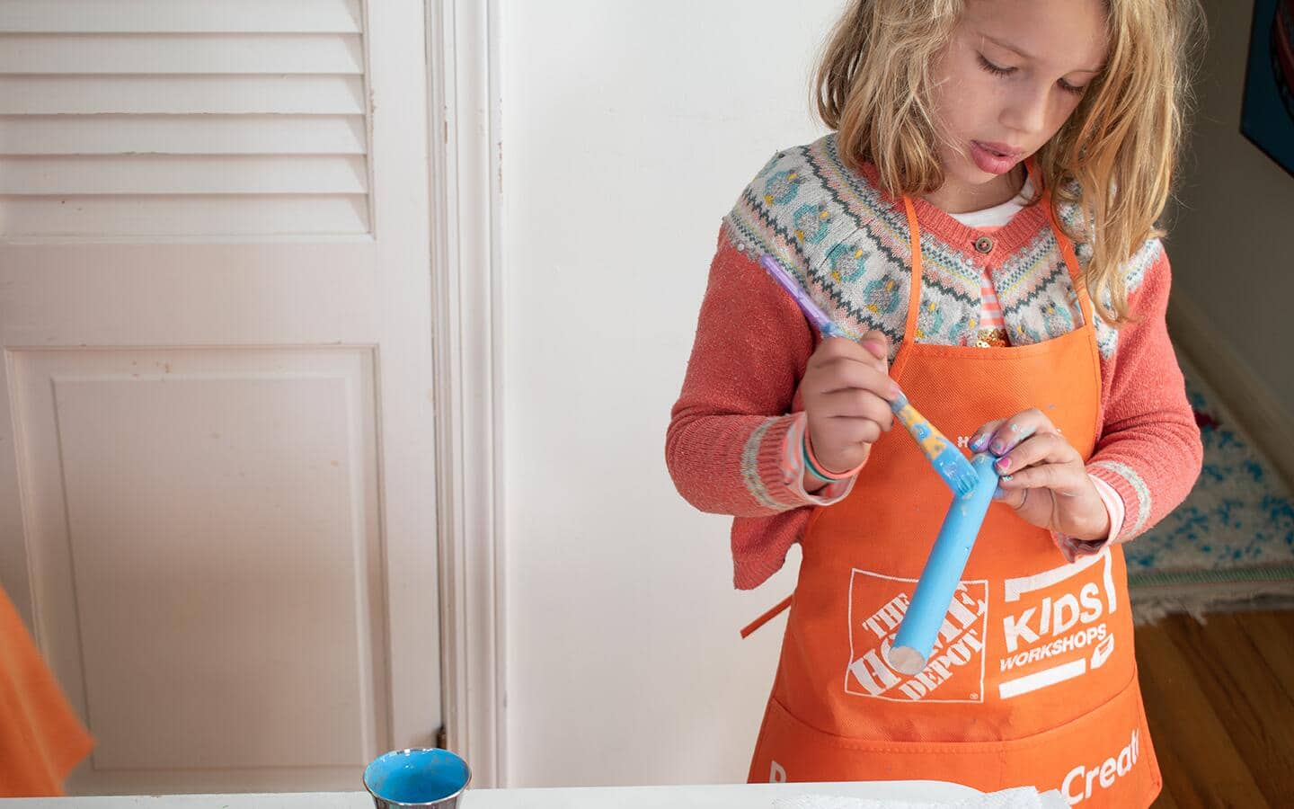 A girl painting a wood dowel blue. A girl painting a wood dowel blue.