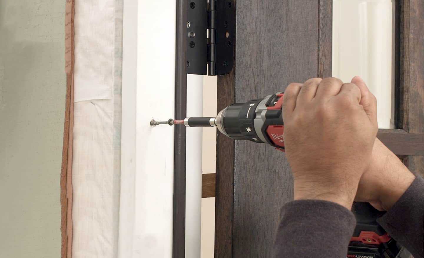 A man securing the bottom of a frame on an entry door to the home.
