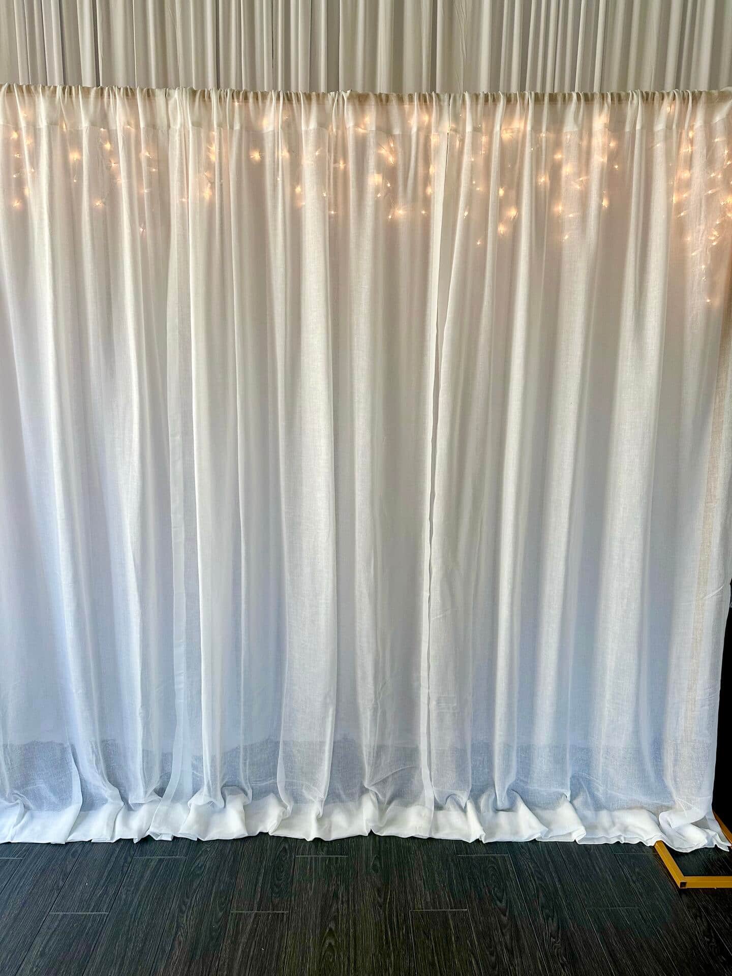 White curtains and string lights on a backdrop stand