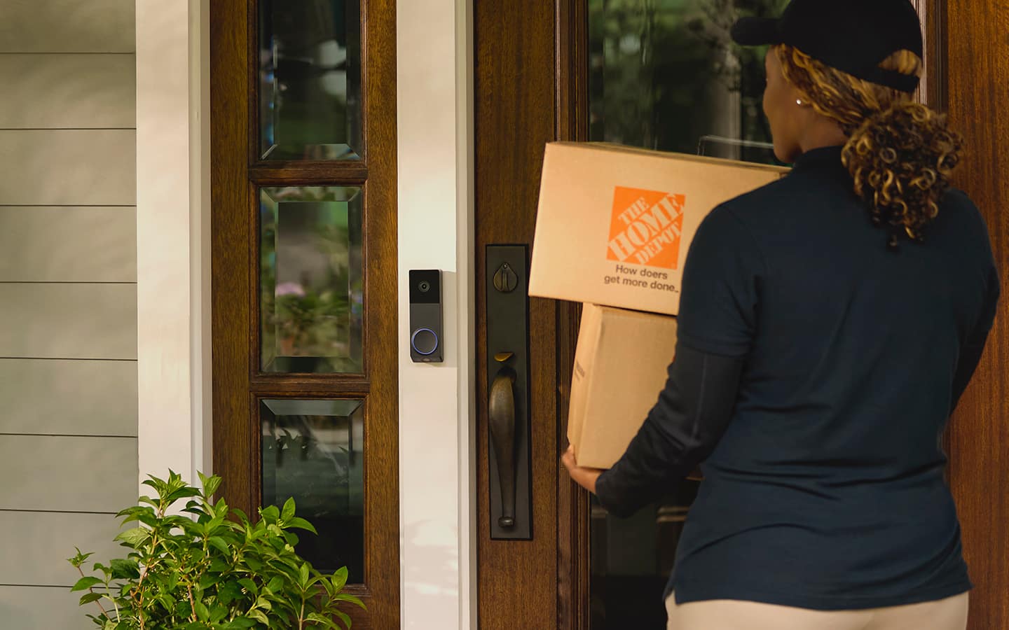 A delivery person holding boxes after ringing a smart doorbell. A delivery person holding boxes after ringing a smart doorbell.