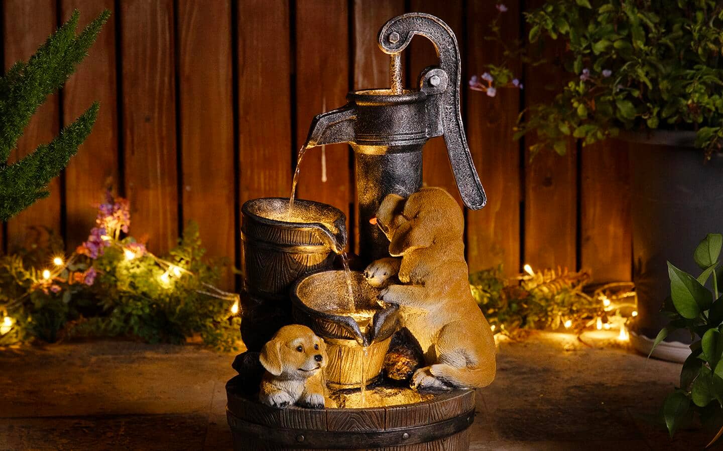 A lighted outdoor fountain designed as a well surrounded by woodland creatures.
