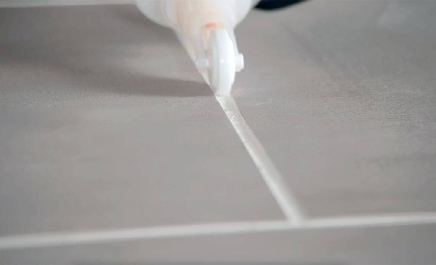 Applying sealer to a grout joint on a tile floor