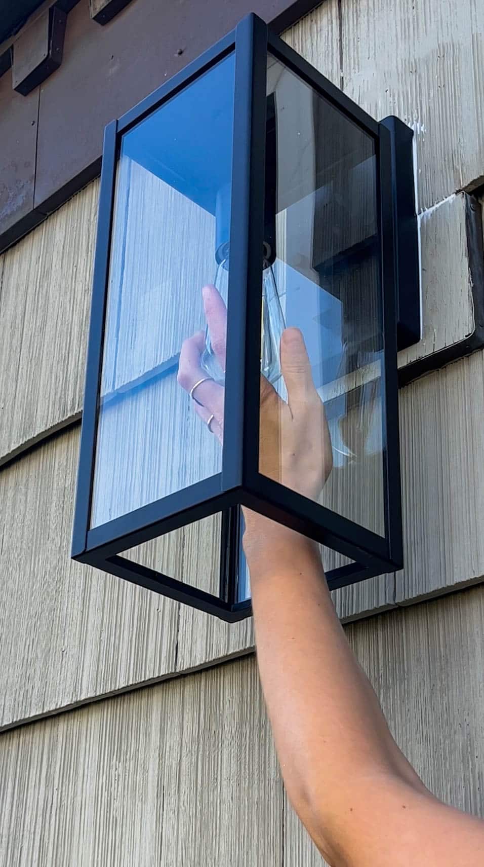 A person installing an outdoor light.