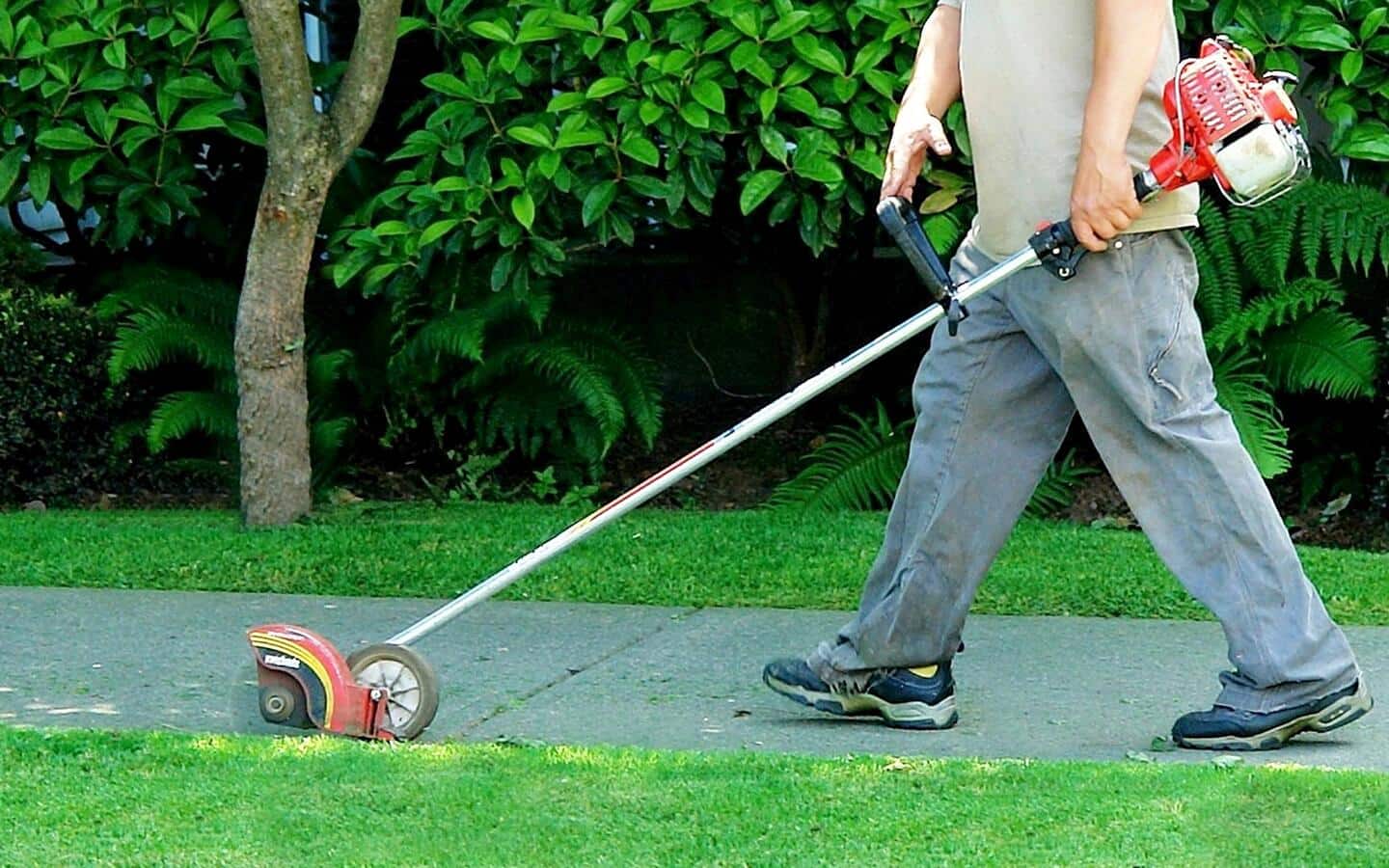 A person using a cordless edge trimmer. A person using a cordless edge trimmer.