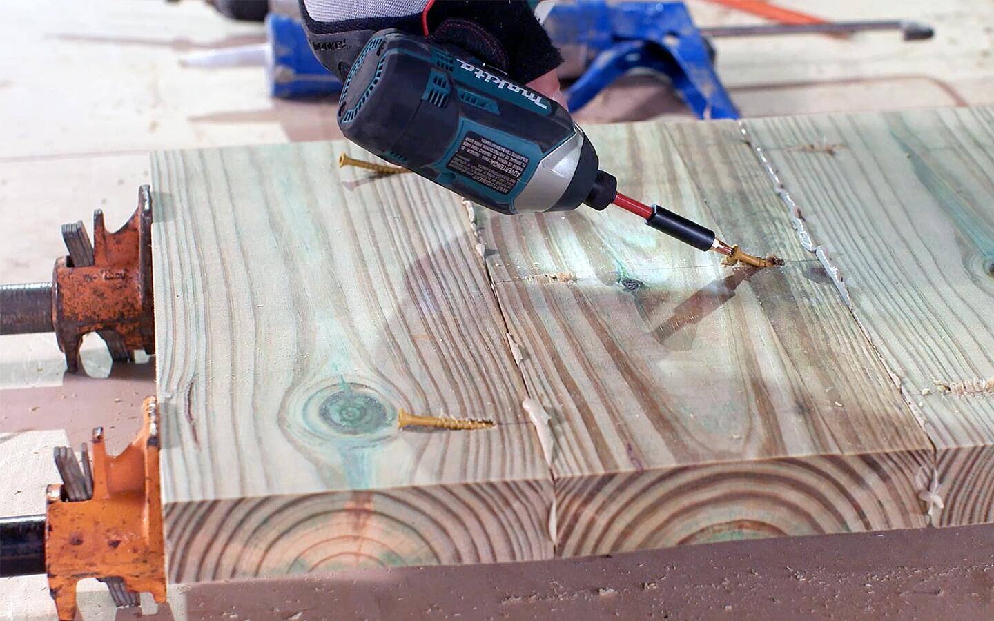 A cordless drill is used to screw into a pocket hole for a grill's wood panels.