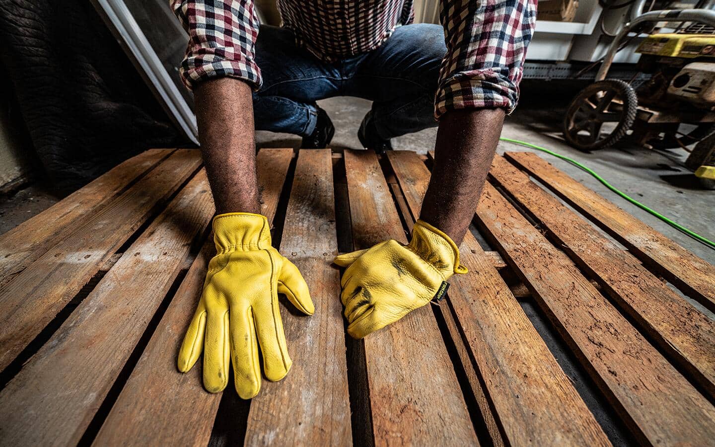 Someone laying down wood planks while wearing work gloves.