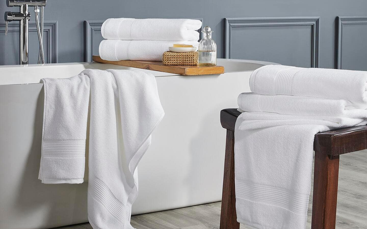 Various white bath towels in stacks and hung over a bathtub.   Various white bath towels in stacks and hung over a bathtub.
